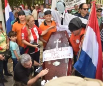 Personas rodeando un cajón funerario que dice "Jubilación IPS Descansen en Paz"