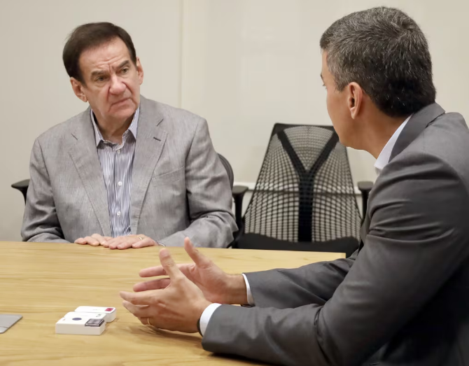 Senador Orlando Penner sentado en una mesa conversando con el Presidente Peña.